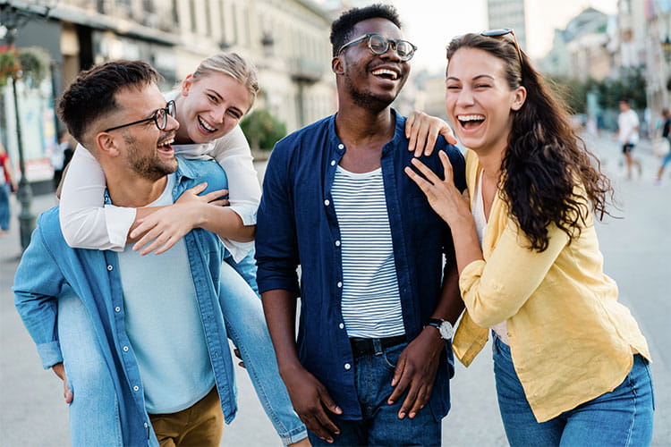 Diverse group of young adults walking outside in the city laughing.
