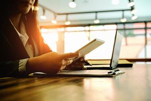 focus on a woman's hands as she uses her cell phone and laptop on a desk