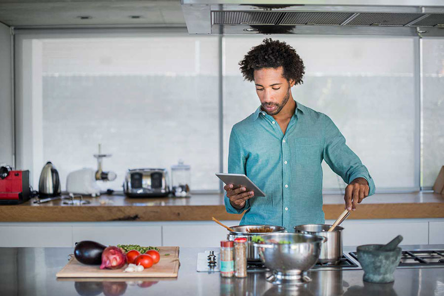 young man reading recipe from tablet while cooking