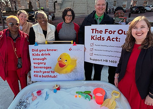 group of health advocates standing in front of kids bath tub filled with sugar