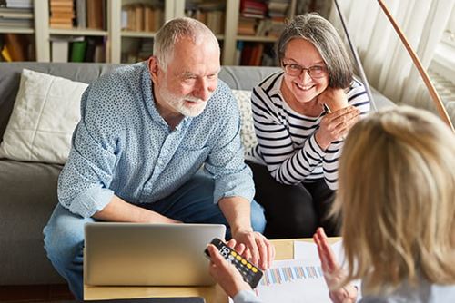 An older couple sitting on a couch and talking with an advisor across the table