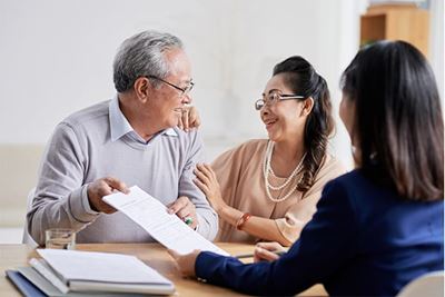 an older couple reviewing documents with an advisor, all seated at a table
