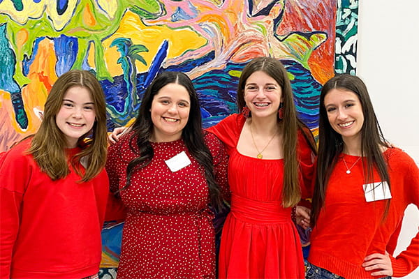 Group of four teen girls wearing red and posing together, smiling
